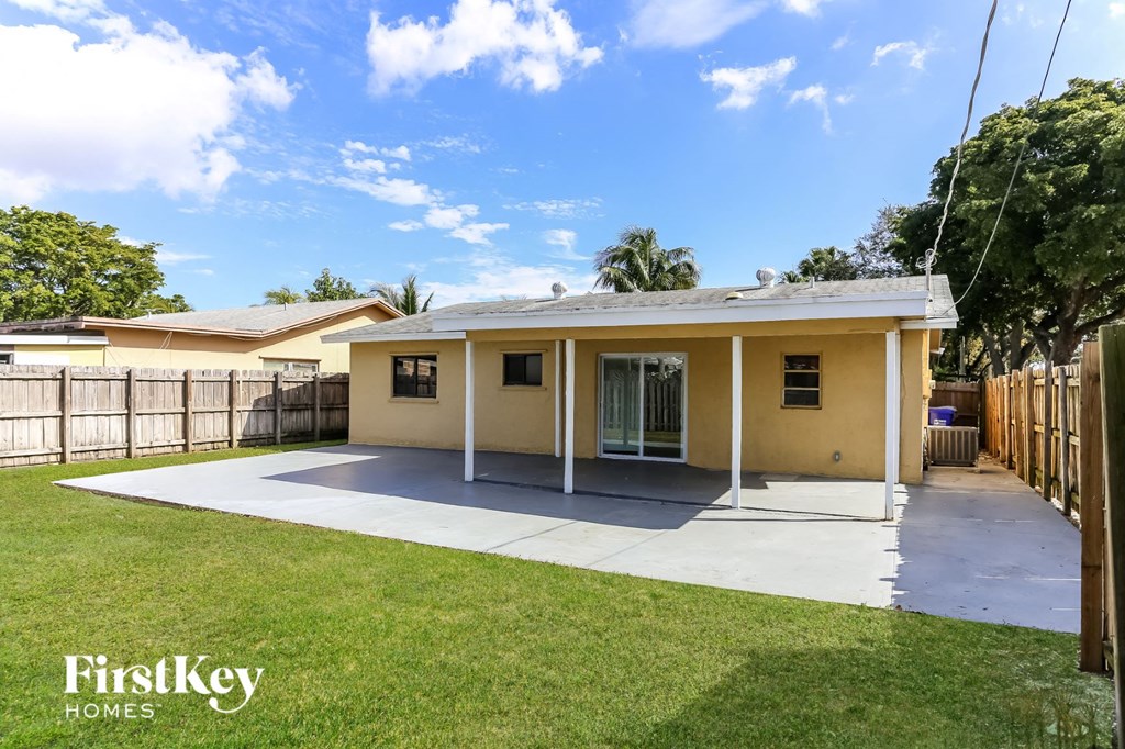 a small yellow house with a driveway and a lawn