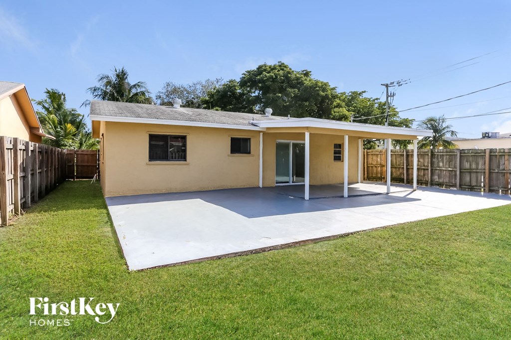 a small yellow house with a patio and a grass yard