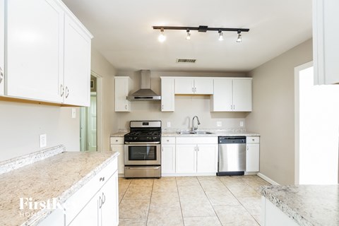 a large kitchen with white cabinets and stainless steel appliances
