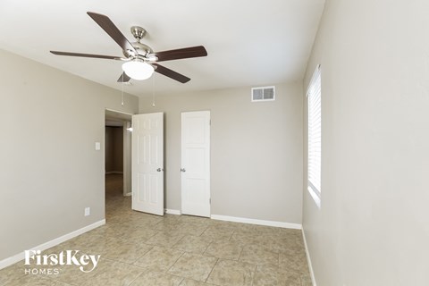a living room with a ceiling fan and a door to a hallway
