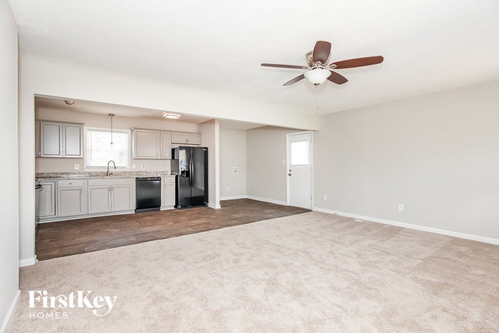 an empty living room and kitchen with a ceiling fan