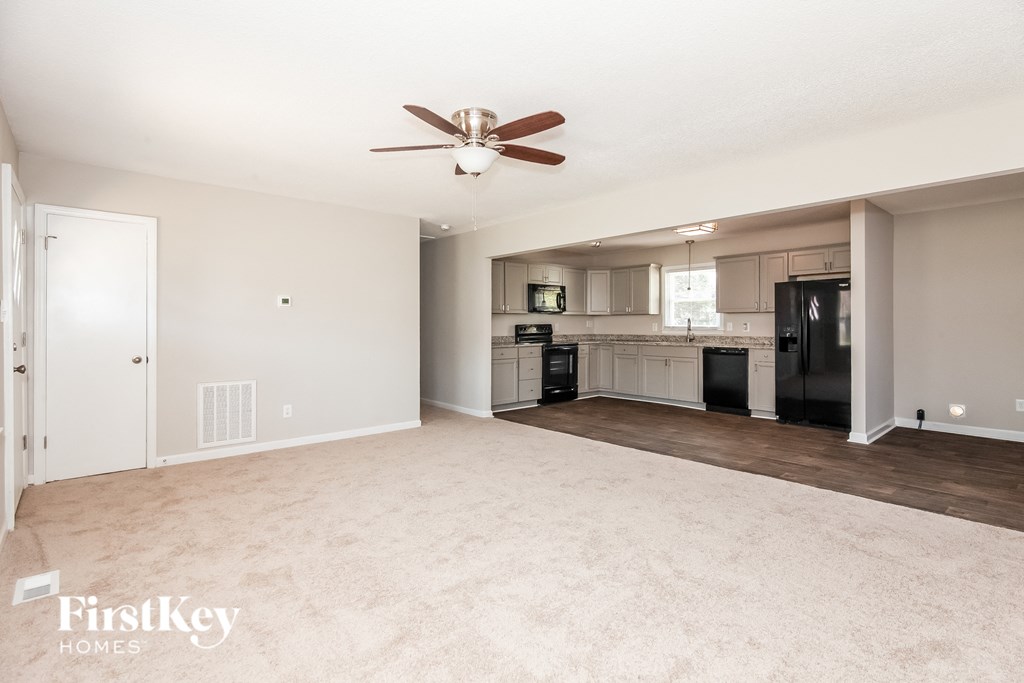 an empty living room and kitchen with a ceiling fan