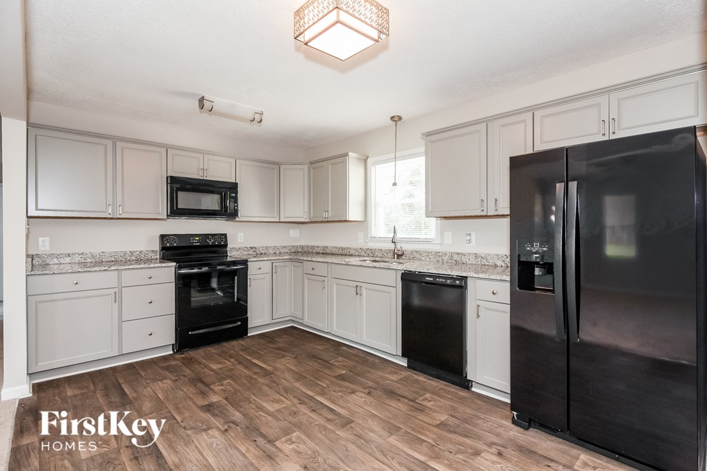 a kitchen with white cabinets and black appliances