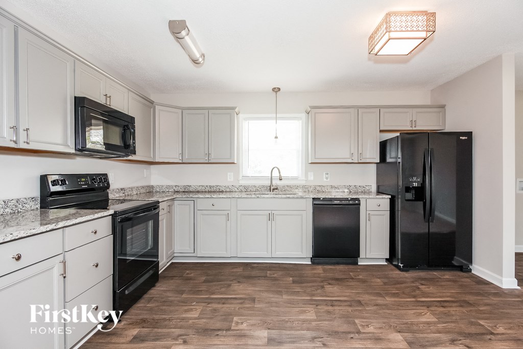 a white kitchen with black appliances and white cabinets