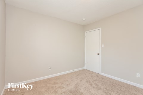a bedroom with beige carpet and a white door