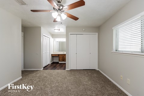 the living room is spacious and has a ceiling fan and a carpet