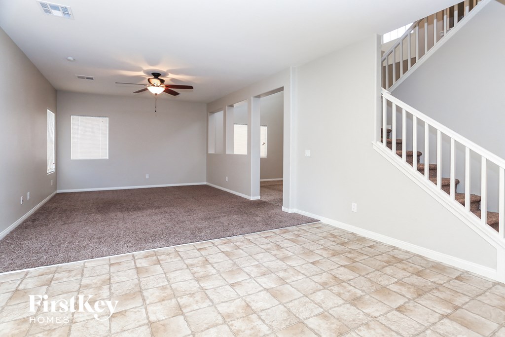 A spacious room with a fan and a staircase.