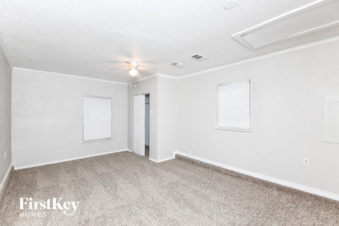A room with a carpeted floor and a ceiling fan.