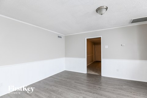 A room with a wooden door and a white wall.