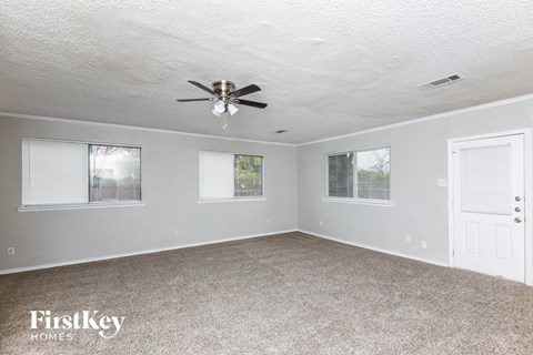 A spacious room with a ceiling fan and carpeted floor.
