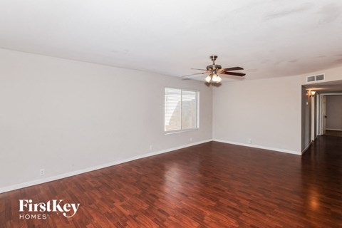 an empty living room with wood floors and a ceiling fan