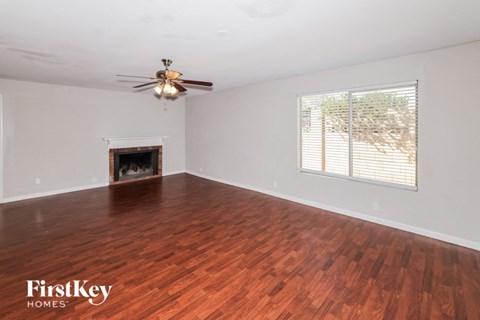 a living room with wood flooring and a fireplace and a ceiling fan