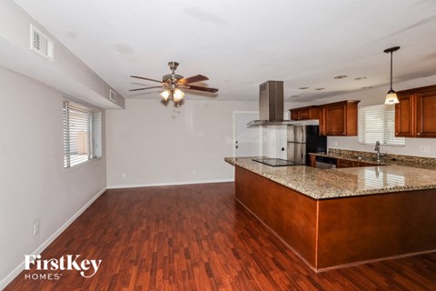 an empty kitchen with an island and a ceiling fan