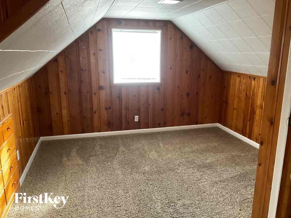 the attic of a home with a carpet floor and a window