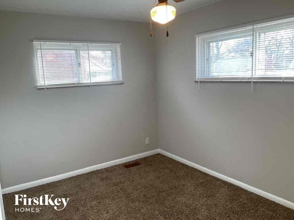 an empty room with a carpeted floor and two windows
