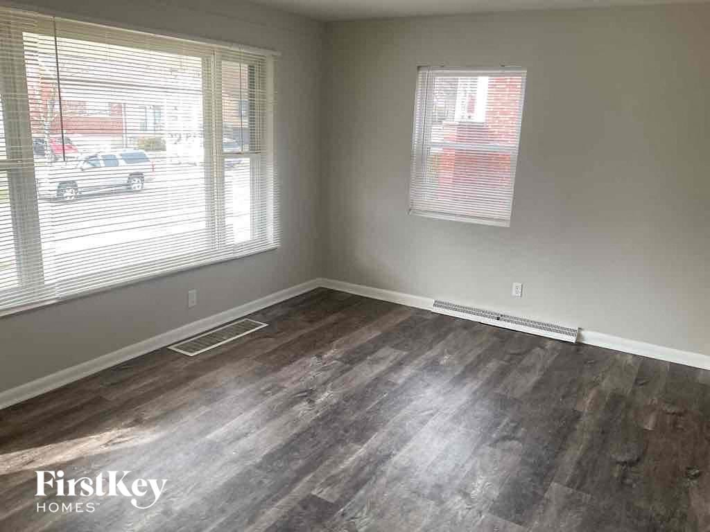 an empty living room with wood floors and a window