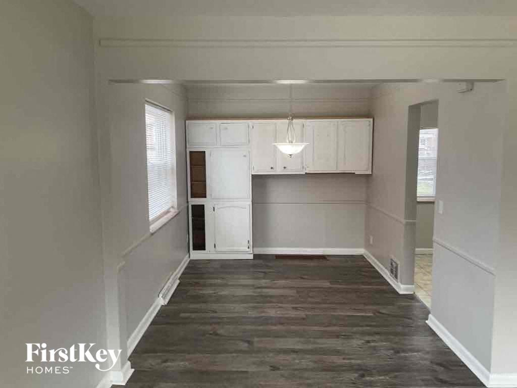 an empty living room with white cabinets and a kitchen