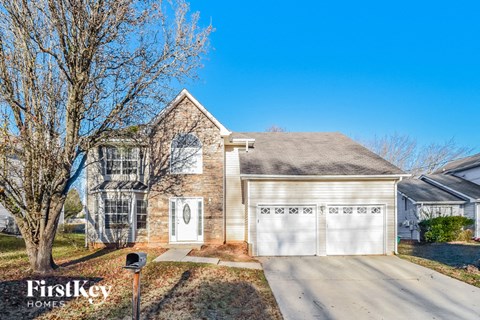 a brick house with a white garage door and a tree