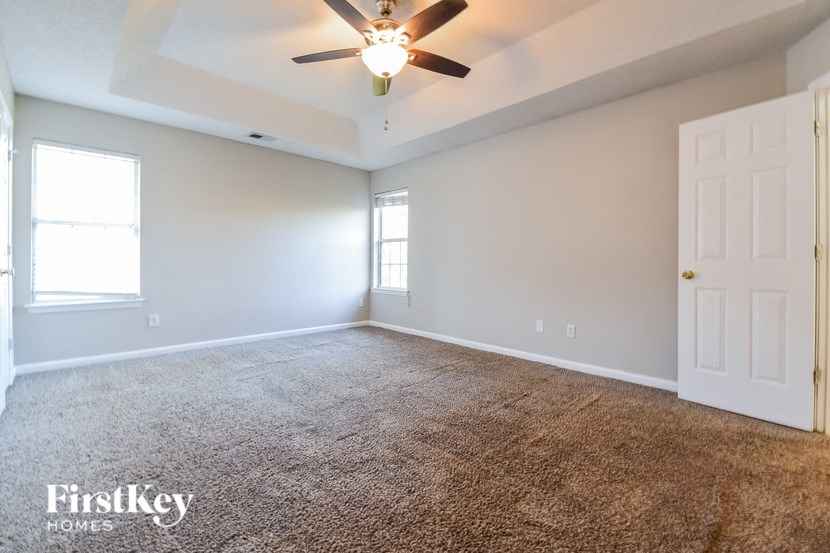 an empty living room with a ceiling fan and a white door