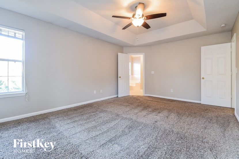 the spacious living room with ceiling fan and carpeting