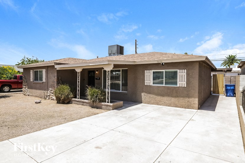a small brown house with a driveway and a garage door