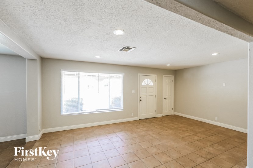 an empty living room with a large window and tiled floors