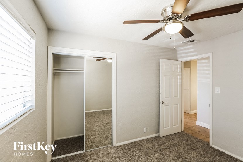 a bedroom with a ceiling fan and a closet