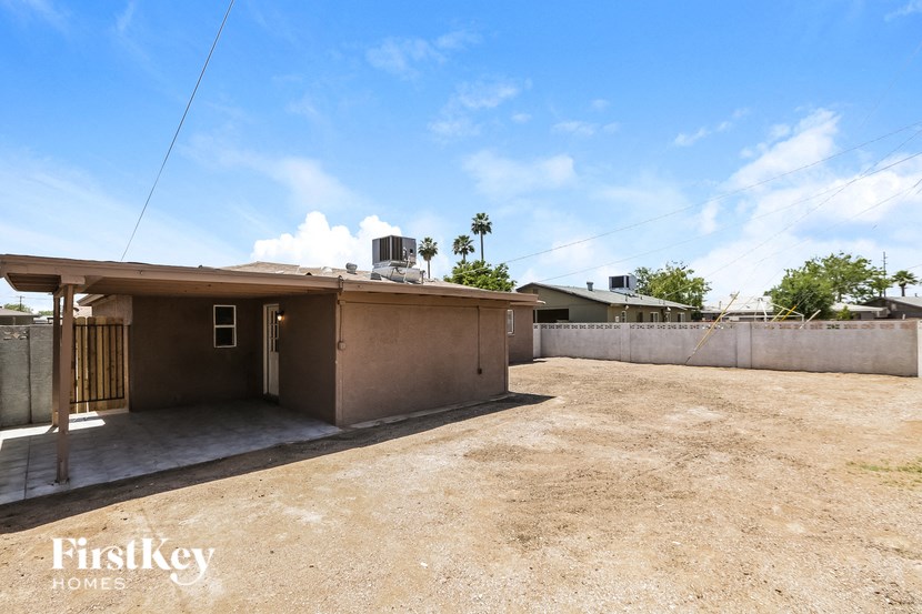 a small house with a dirt lot and a fence