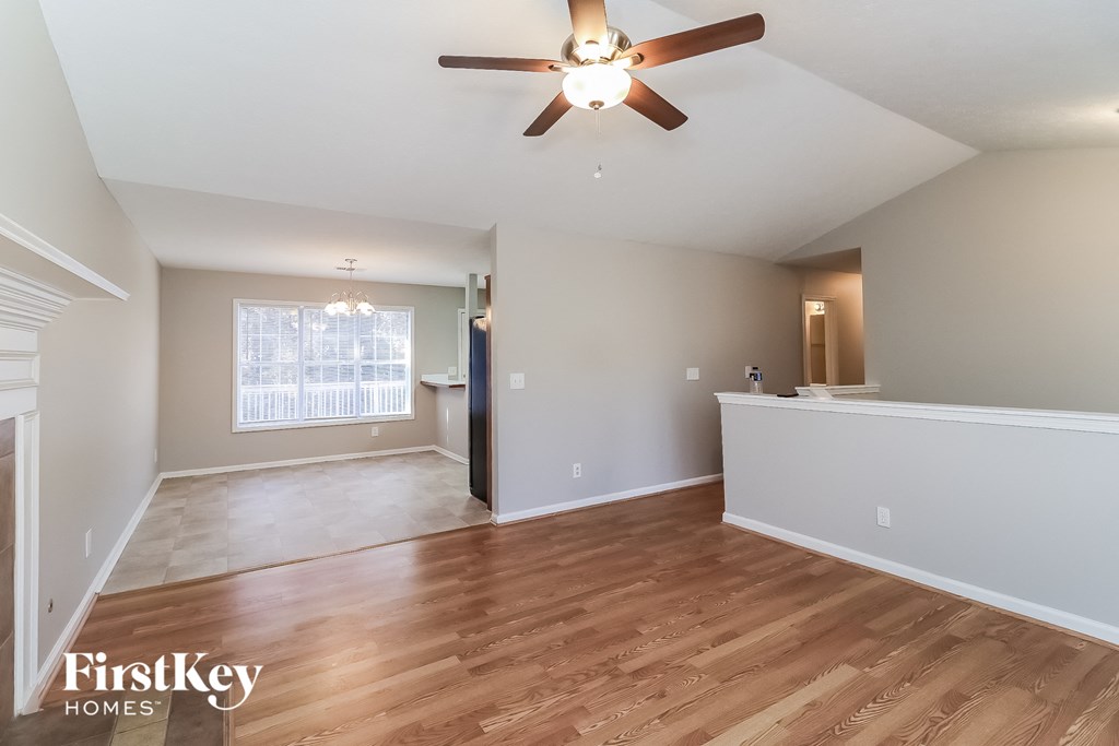 an empty living room with a ceiling fan and wood flooring