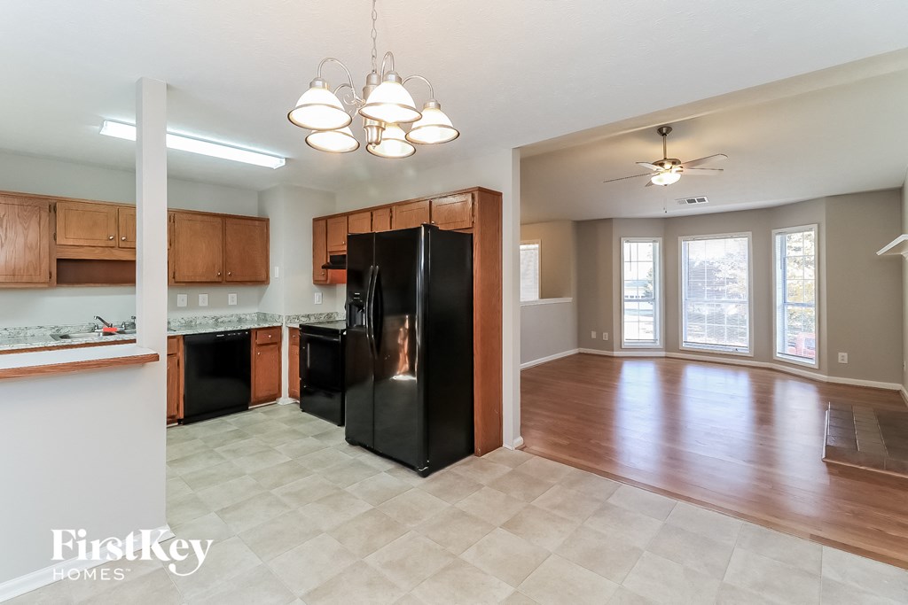an empty kitchen and living room with a black refrigerator