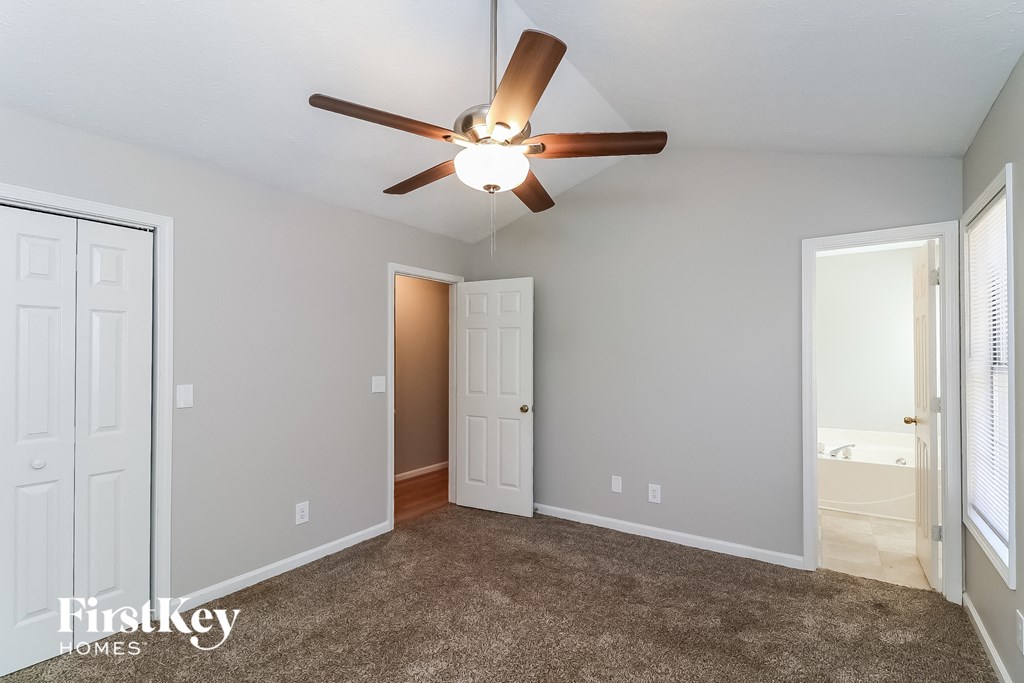 a bedroom with a ceiling fan and a door to a closet