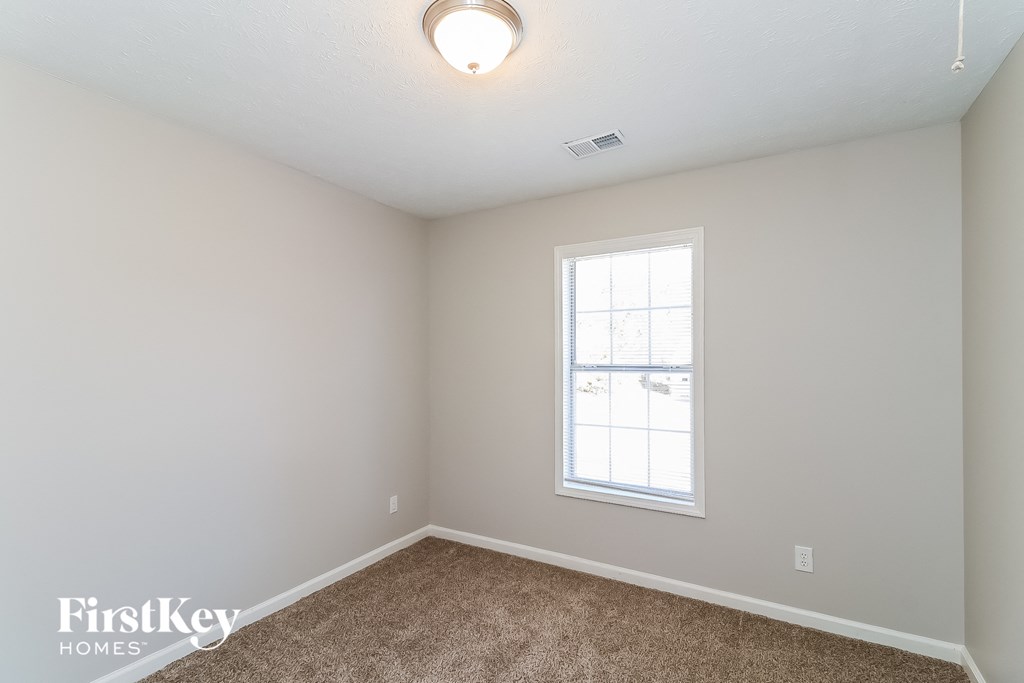 a bedroom with white walls and carpet and a window