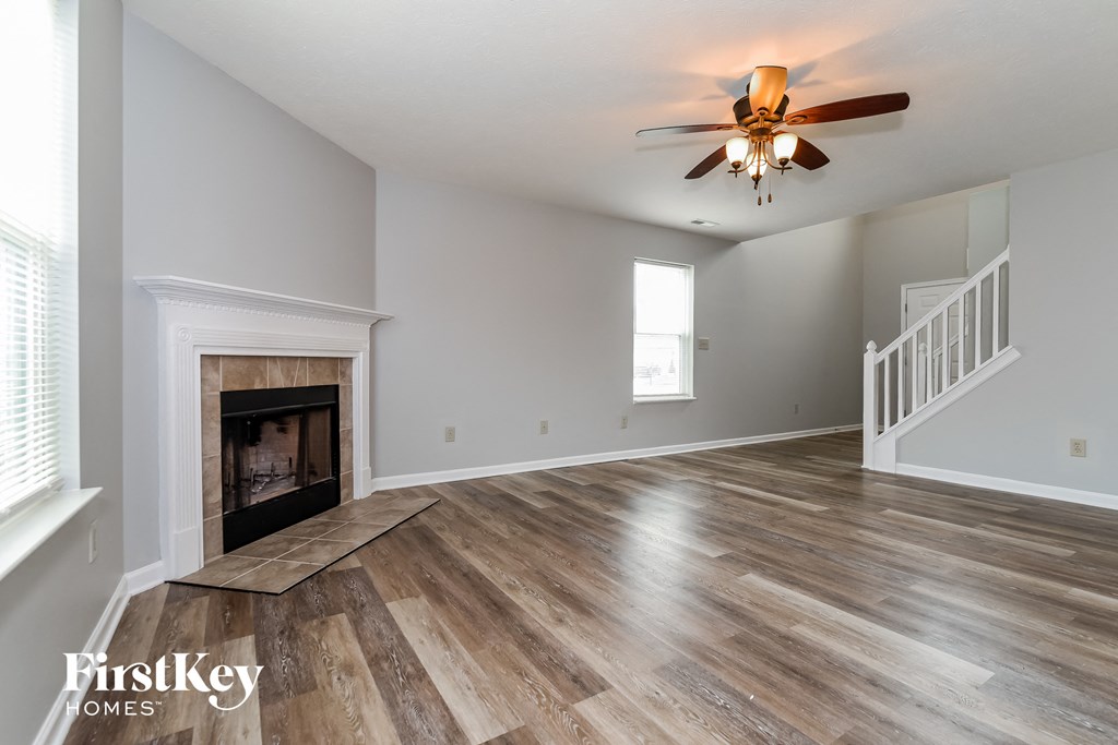 A spacious room with a fireplace and wooden flooring.