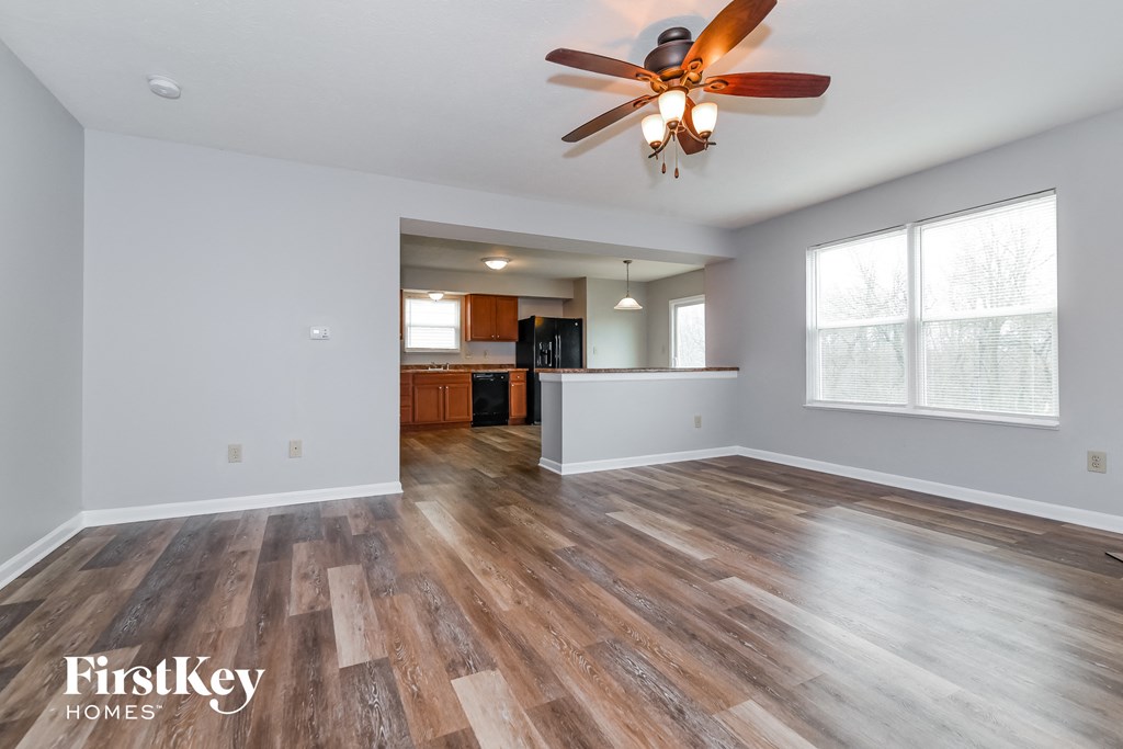 A spacious room with wooden flooring and a ceiling fan.