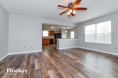 A spacious room with wooden flooring and a ceiling fan.