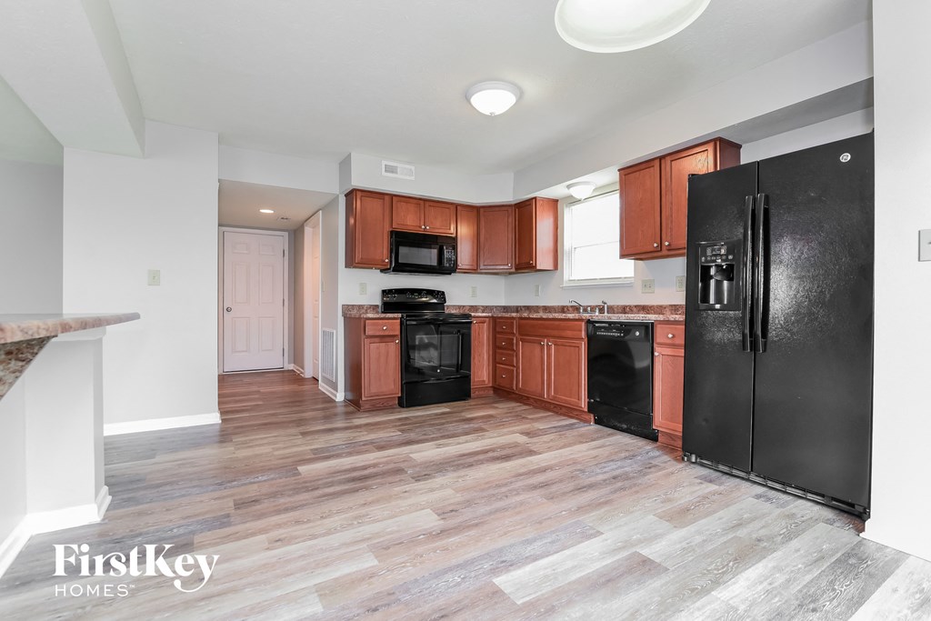 A kitchen with wooden cabinets and black appliances.
