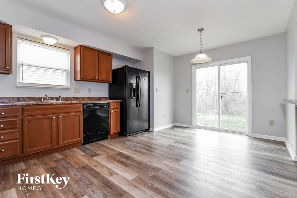 A kitchen with wooden cabinets and a black fridge.