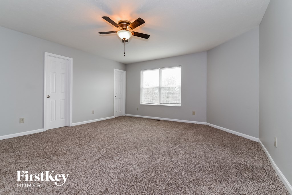 A spacious room with a ceiling fan and carpeted floor.
