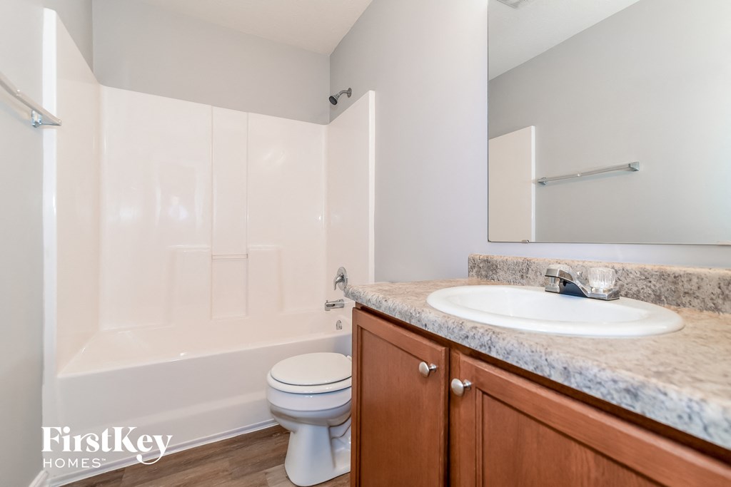 A bathroom with a white toilet and a marble countertop.