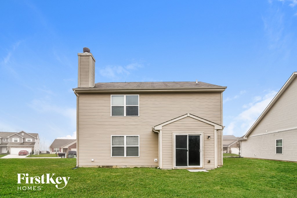 A house with a beige exterior and a chimney is for sale by FirstKey Homes.