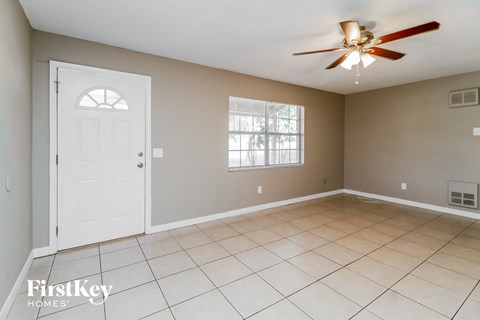 an empty living room with a white tile floor and a ceiling fan
