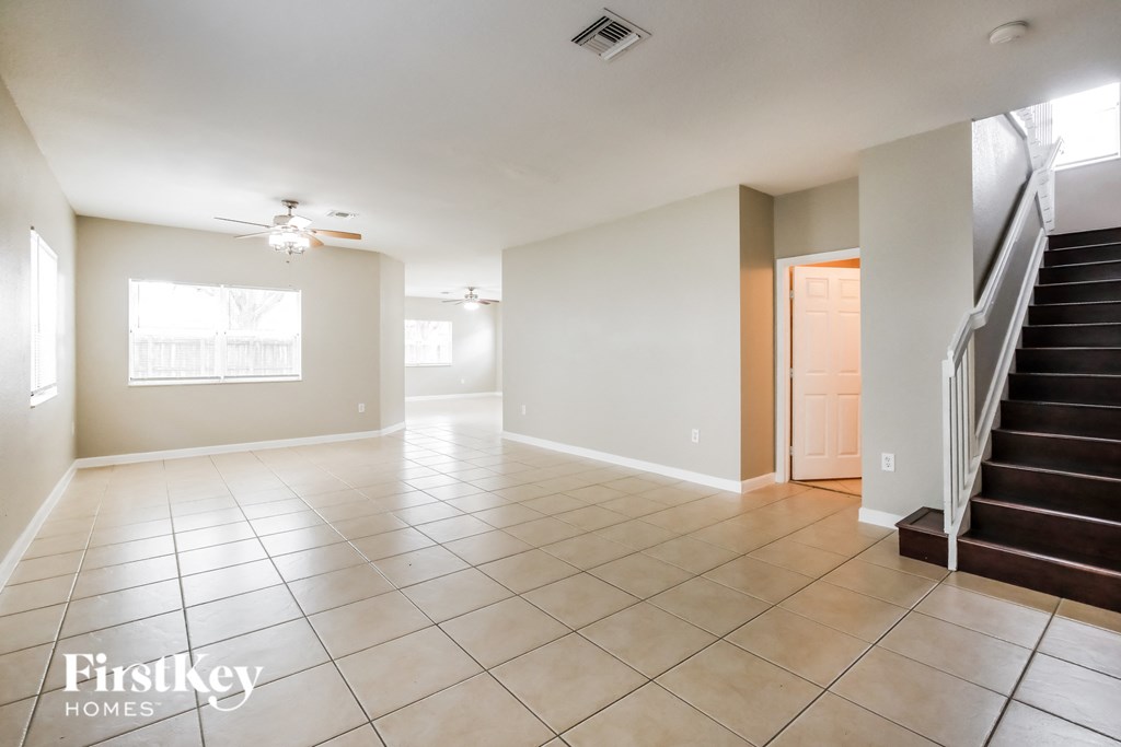 an empty living room with a staircase and tile flooring