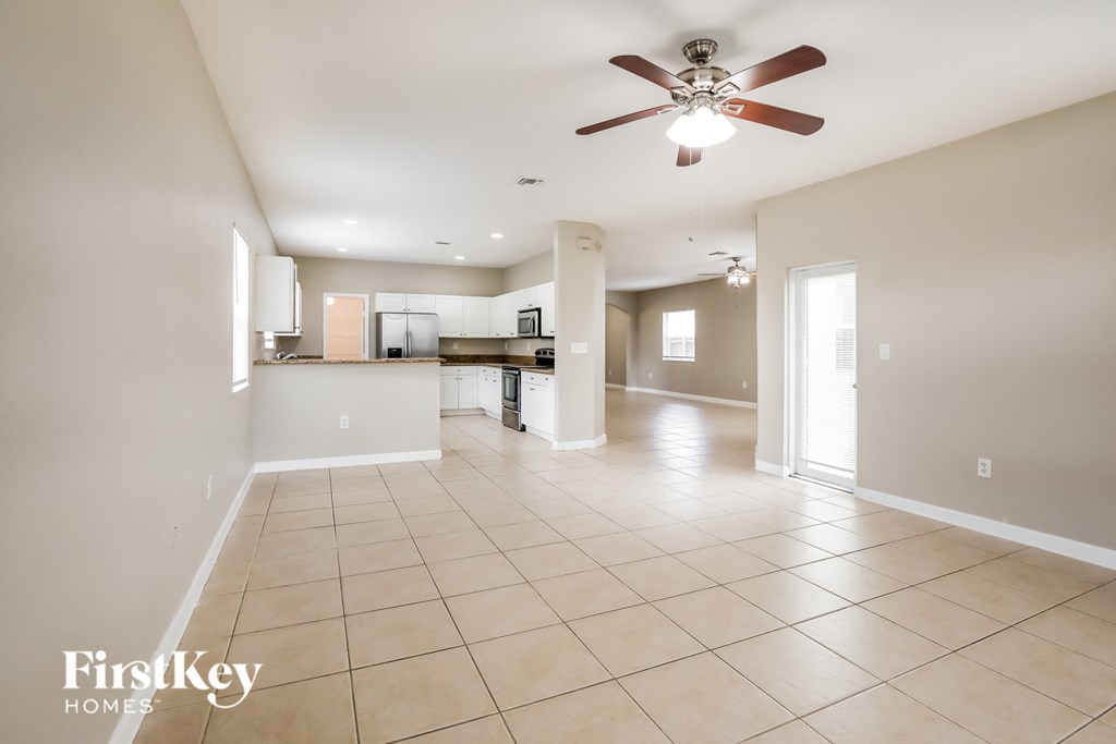 an empty living room and kitchen with a ceiling fan