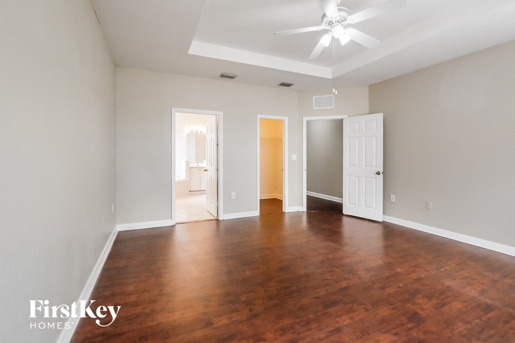 an empty living room with wood flooring and a ceiling fan