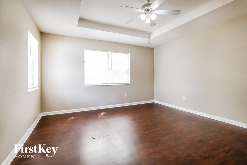 a empty living room with wooden floors and a ceiling fan