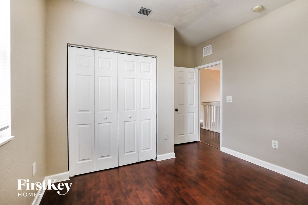 the living room of an empty home with white closets and wood floors
