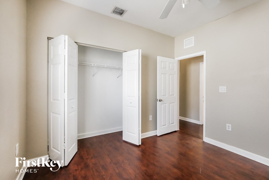 a bedroom with two closets and a hard wood floor