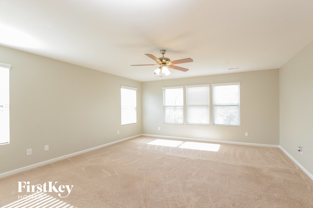 an empty living room with a ceiling fan and a window