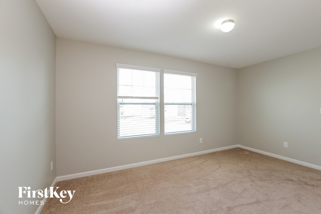 a bedroom with two windows and a carpeted floor