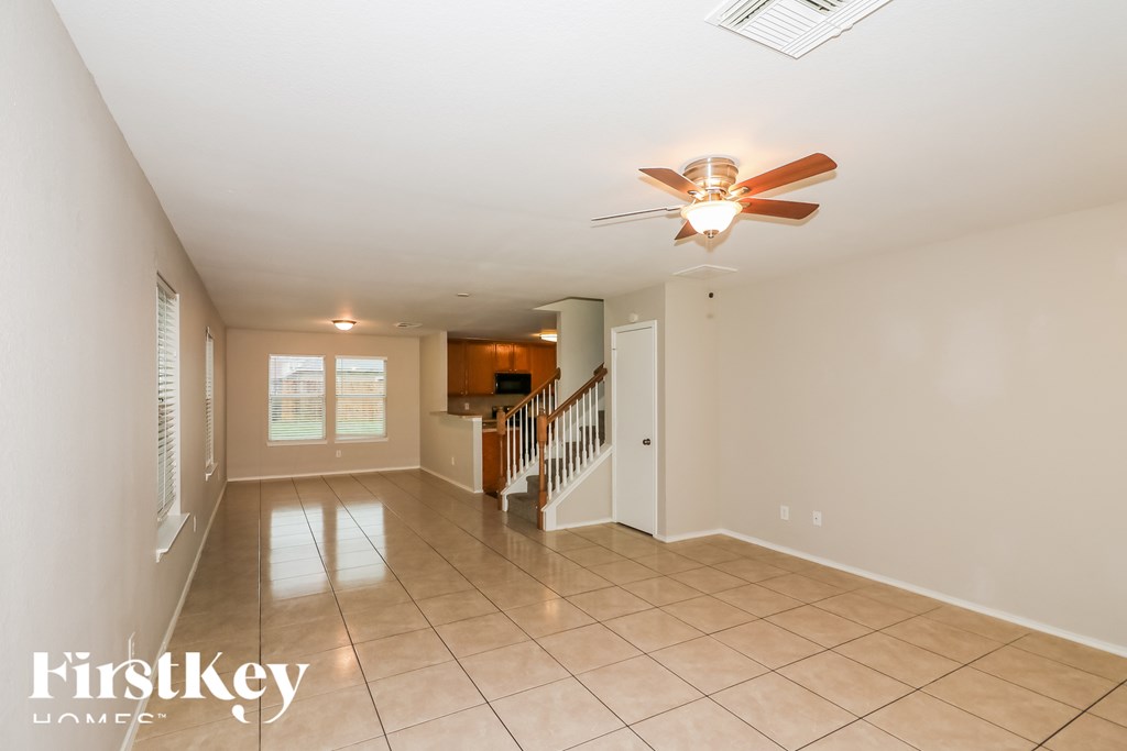 A spacious room with a fan and a staircase.
